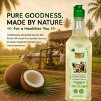 Nandi's Blessing pure bull-pressed coconut oil bottle displayed beside raw coconuts and palm leaves.